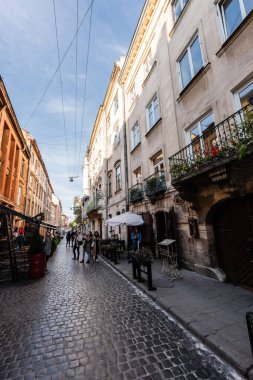 LVIV, UKRAINE - 23 Ekim 2019: Sokak kafesi ve şehir merkezindeki dar cadde boyunca yürüyen insanlar