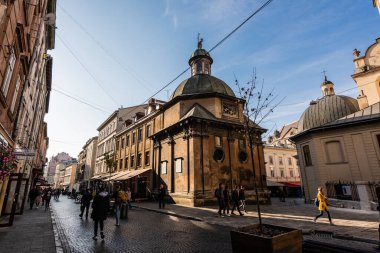 LVIV, UKRAINE - 23 Ekim 2019: Boim Şapeli 'nin kuzey cephesi ve cadde boyunca yürüyen insanlar