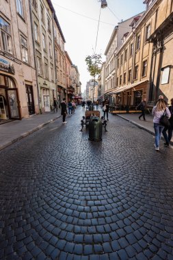 LVIV, UKRAINE - 23 Ekim 2019: eski binalar ve şehir merkezinde cadde boyunca yürüyen insanlar