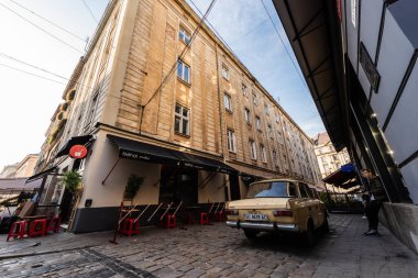 LVIV, UKRAINE - 23 Ekim 2019: Çadırında harfleri olan klasik araba ve kafenin yanında duran adam
