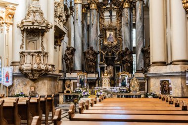 LVIV, UKRAINE - OCTOBER 23, 2019: interior of dominican church with wooden benched and gilded decorative elements clipart