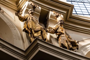 LVIV, UKRAINE - OCTOBER 23, 2019: low angle view of gilded male statues in dominican church clipart