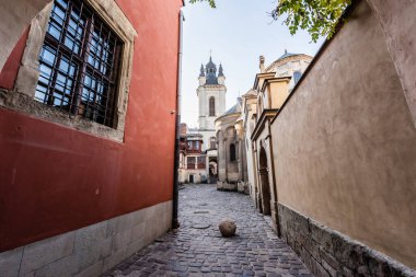 red house near monastery wall and carmelite church against blue sky in lviv, ukraine clipart