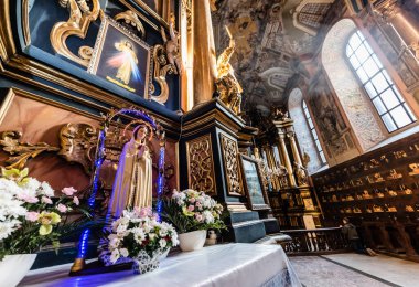 LVIV, UKRAINE - OCTOBER 23, 2019: altar with our lady statue, decorated with natural flowers in carmelite church clipart
