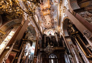 LVIV, UKRAINE - OCTOBER 23, 2019: low angle view of columns and ceiling with beautiful paintings in carmelite church clipart