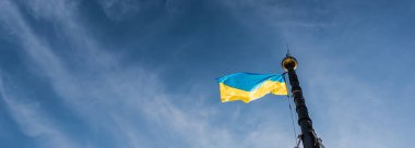 horizontal image of ukrainian flag on flagpole against blue sky in lviv, ukraine clipart