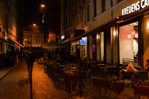 Львов, Украина - 23 октября 2019 года: надписи на креденсах на здании возле террасы со стульями и столами
 