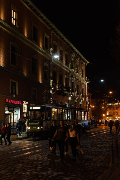 Львов, Украина - 23 октября 2019 года: трамвай возле людей, идущих по улице вечером
 