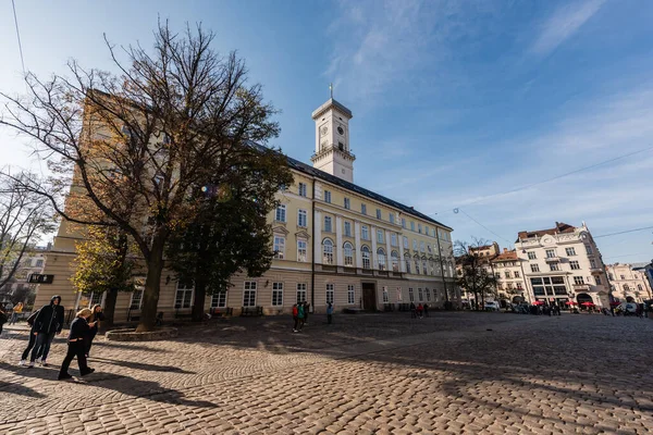 LVIV, UKRAINE - 23 Ekim 2019: lviv belediye kulesi cephesi ve sokak boyunca yürüyen insanlar