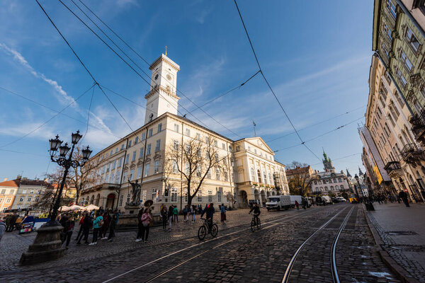 LVIV, UKRAINE - OCTOBER 23, 2019: people and vehicles near lviv city hall