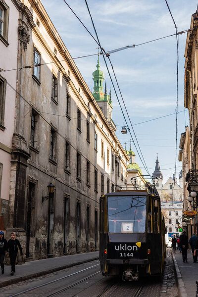 LVIV, UKRAINE - OCTOBER 23, 2019: tram with uklon lettering on narrow street in city center