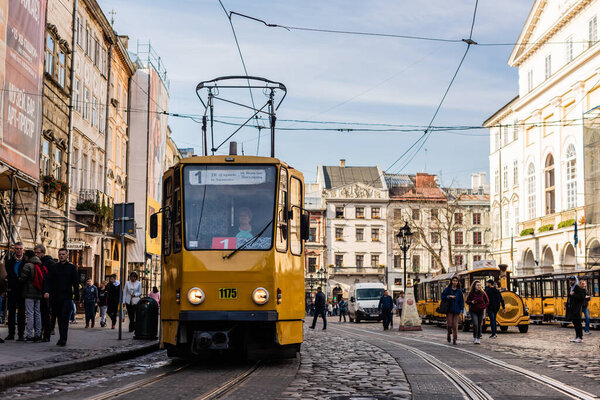 LVIV, UKRAINE - OCTOBER 23, 2019: tram with route number one lettering and people walking along street in city center