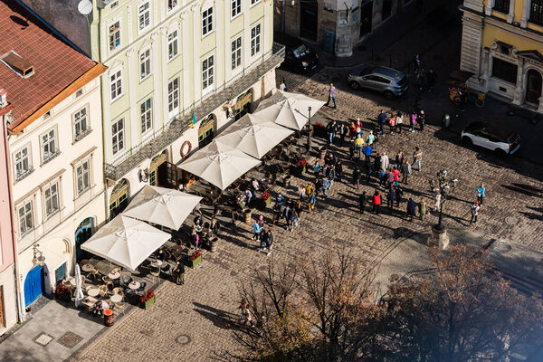 LVIV, UKRAINE - OCTOBER 23, 2019: aerial view of people walking near street cafe on market square
