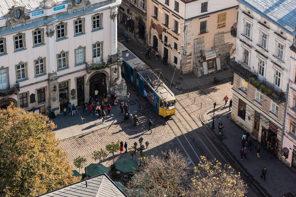 LVIV, UKRAINE - OCTOBER 23, 2019: aerial view of tram crossing crossroad and people walking on street