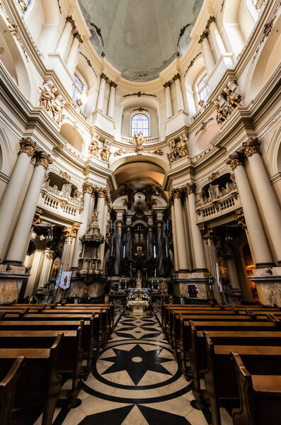 LVIV, UKRAINE - OCTOBER 23, 2019: interior of dominican church with wooden benches, mosaic floor and columns with gilded decoration