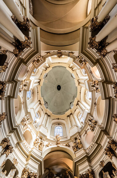 LVIV, UKRAINE - OCTOBER 23, 2019: bottom view of ceiling and columns with gilded decoration in dominican church 