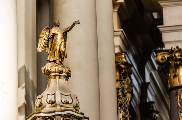 LVIV, UKRAINE - OCTOBER 23, 2019: gilded statue of archangel holding bible in outstretched hand in dominican church