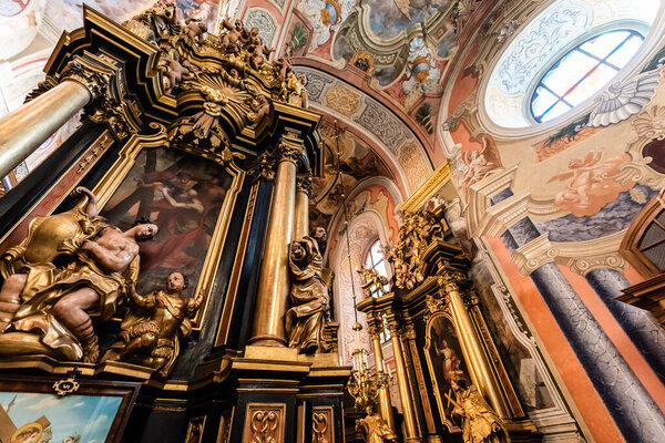 LVIV, UKRAINE - OCTOBER 23, 2019: low angle view of carmelite church interior with gilded statues and columns
