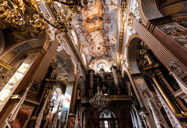 LVIV, UKRAINE - OCTOBER 23, 2019: low angle view of columns and ceiling with beautiful paintings in carmelite church