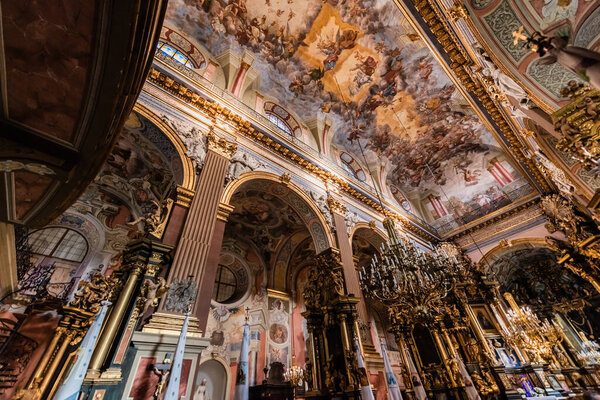 LVIV, UKRAINE - OCTOBER 23, 2019: interior of carmelite church with beautiful paintings on ceiling and gilded chandeliers
