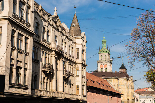 neoclassical buildings and korniakt tower against blue sky in lviv, ukraine