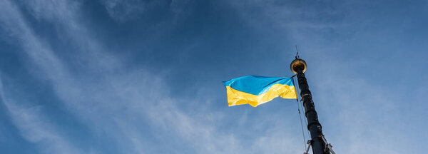 горизонтальное изображение украинского флага на флагштоке против голубого неба во Львове, Украина
