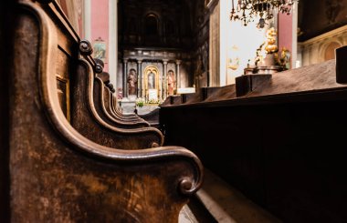 LVIV, UKRAINE - 23 Ekim 2019: Carmelite kilisesindeki ahşap bankların seçici odak noktası
