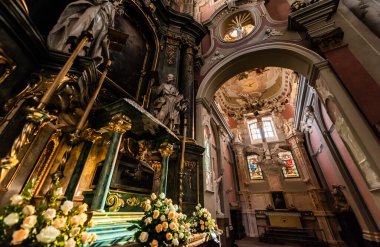 LVIV, UKRAINE - OCTOBER 23, 2019: low angle view of carmelite church interior decorated with gilding, sculptures and natural flowers clipart
