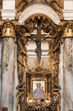 LVIV, UKRAINE - OCTOBER 23, 2019: icon and crucifix between marble columns with gilded decoration in dominikan church clipart