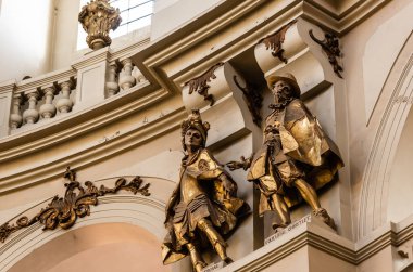 LVIV, UKRAINE - 23 Ekim 2019: Dominik kilisesinde kemer ve balustrade yakınlarındaki yaldızlı erkek heykelleri