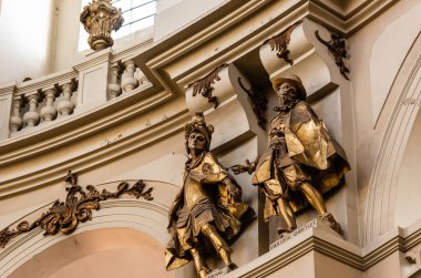 LVIV, UKRAINE - OCTOBER 23, 2019: gilded male statues in dominican church near arches and balustrade clipart