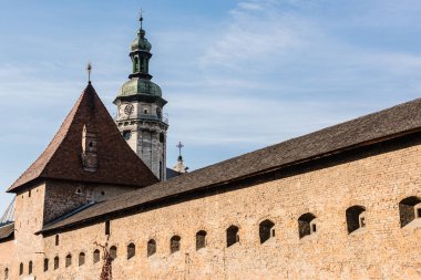 korniakt tower and carmelite monastery wall against blue sky in lviv, ukraine clipart