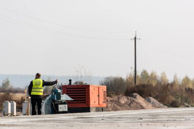 LVIV, UKRAINE - 23 Ekim 2019: yol çalışması sırasında jeneratör motorunu çalıştıran işçilerin arka görünümü 