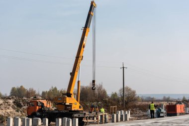 LVIV, UKRAINE - 23 Ekim 2019: Dakika harfli kamyon ve vinç ve Kiril yazıtlı ve otoyoldaki işçilere yakın beton bloklar
