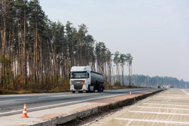 LVIV, UKRAINE - 23 Ekim 2019: Ağaçlar boyunca otobanda ilerleyen sarnıç ve daf yazıtlı kamyon