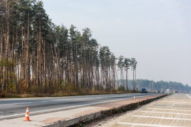 LVIV, UKRAINE - 23 Ekim 2019: Ukrayna 'da ışıklı farlarla hareket eden otoyol kenarındaki yol çalışması konileri