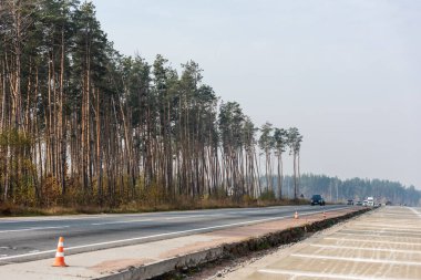 LVIV, UKRAINE - OCTOBER 23, 2019: roadwork cones near highway with car moving with lighting headlamps in ukraine clipart