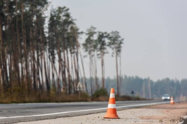 roadwork cones near highway with car moving with lighting headlamps in ukraine clipart
