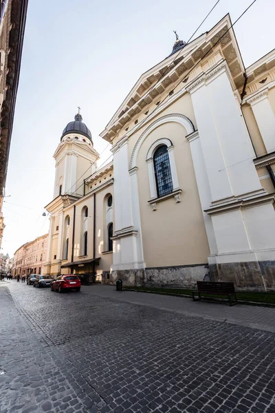 LVIV, UKRAINE - 23 Ekim 2019: Carmelite Manastırı Duvarı ve Kilisesi, ve caddeye park edilmiş arabalar