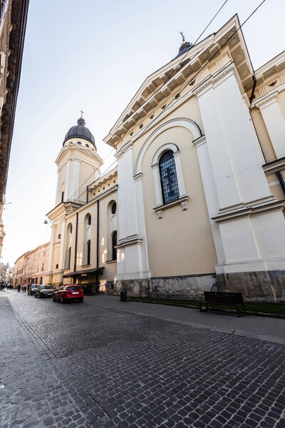 LVIV, UKRAINE - OCTOBER 23, 2019: carmelite monastery wall and church, and cars parked on street