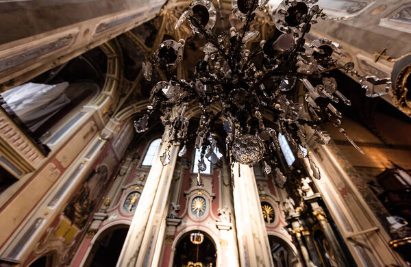LVIV, UKRAINE - OCTOBER 23, 2019: low angle view of chandelier and columns in lviv latin cathedral