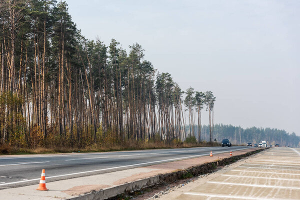 LVIV, UKRAINE - OCTOBER 23, 2019: roadwork cones near highway with car moving with lighting headlamps in ukraine