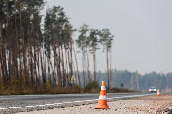 roadwork cones near highway with car moving with lighting headlamps in ukraine