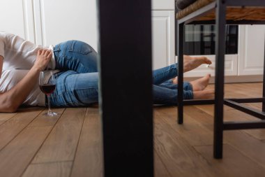 Kırpılmış kırmızı şarap kadehinin yanında yerde yatan çiftin görüntüsü 