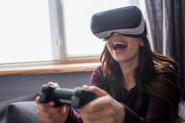KYIV, UKRAINE - 15 Mayıs 2020: video oyunu oynarken elinde joystick tutan heyecanlı kızın seçici odak noktası