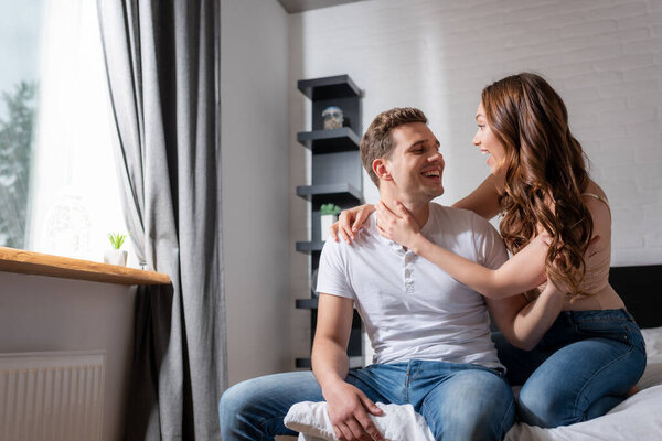 cheerful couple looking at each other and smiling in bedroom 
