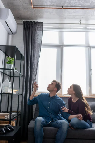 Hombre Mujer Mirando Aire Acondicionado Mientras Están Sentados Sofá — Foto de Stock