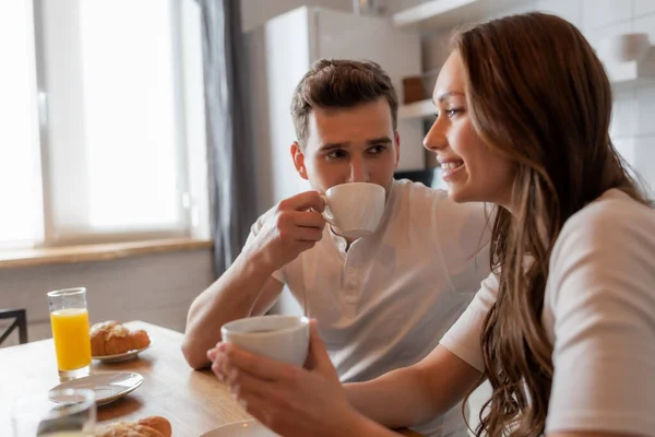 Selective Focus Man Drinking Coffee Looking Cheerful Girlfriend Kitchen — Stock Photo, Image