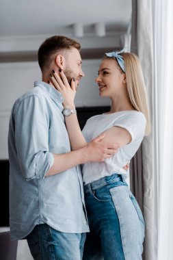 Gülümseyen kadın evde yakışıklı erkek arkadaşının yüzüne dokunuyor. 