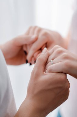 Nişan yüzüğü parmağında bir erkekle el ele tutuşan kadın görüntüsü. 